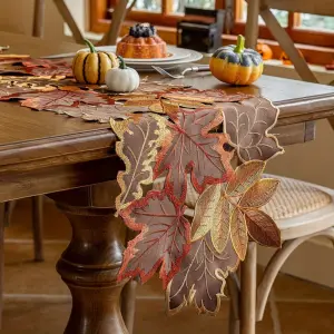 Tischläufer in Blattform mit gestickten Herbstblättern in Braun, Orange und Gold auf einem Tisch