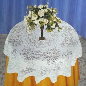 Weiße runde Tischdecke mit Spitzenmuster auf einem Tisch mit Blumenstrauß