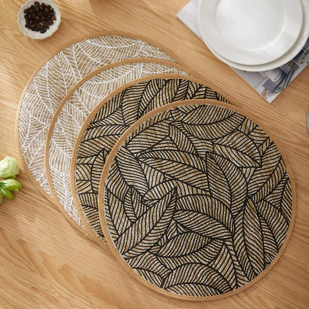 Runde Platzdeckchen mit Blattmuster in Schwarz und Weiß auf Holztisch