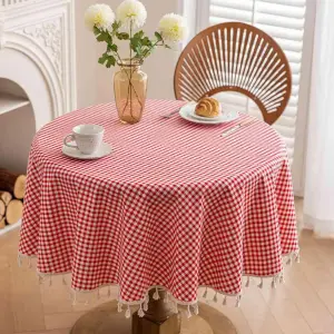 Runde rot-weiß karierte Tischdecke mit Quasten auf rundem Tisch mit Tasse und Croissant