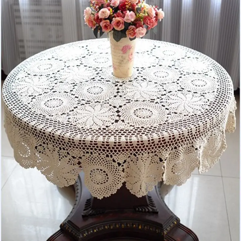 Runde gehäkelte Spitzentischdecke in Creme auf einem Tisch mit Blumen