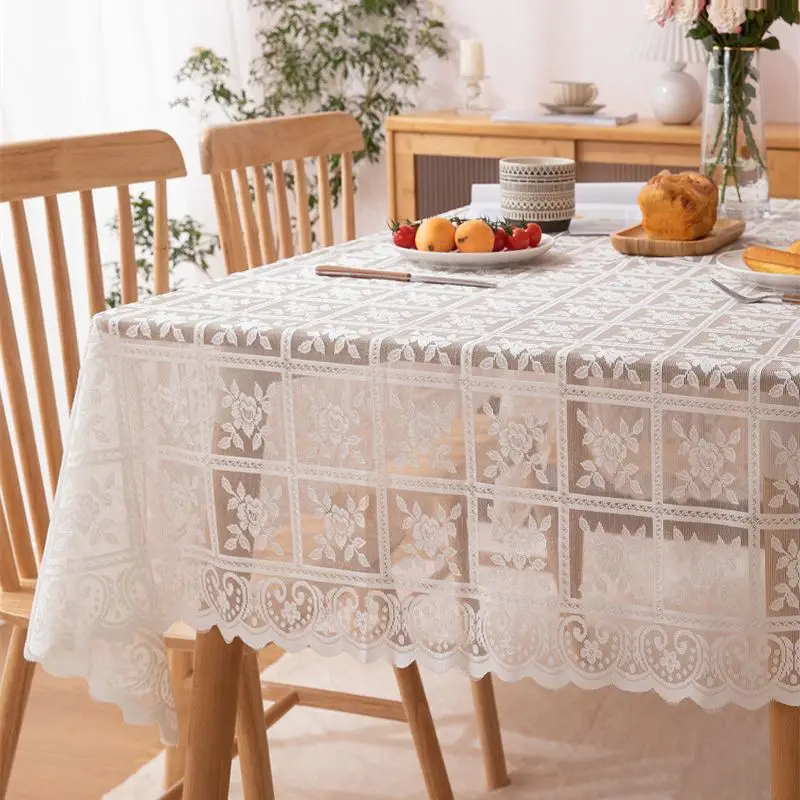 Weiße Spitzentischdecke mit Rosenmuster auf einem rechteckigen Holztisch mit gedecktem Frühstück