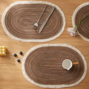 Ovale braune Tischsets mit heller Fransenkante auf Holztisch mit Besteck