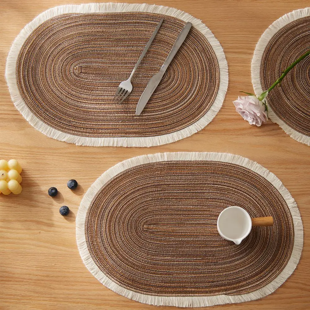 Ovale braune Tischsets mit heller Fransenkante auf Holztisch mit Besteck