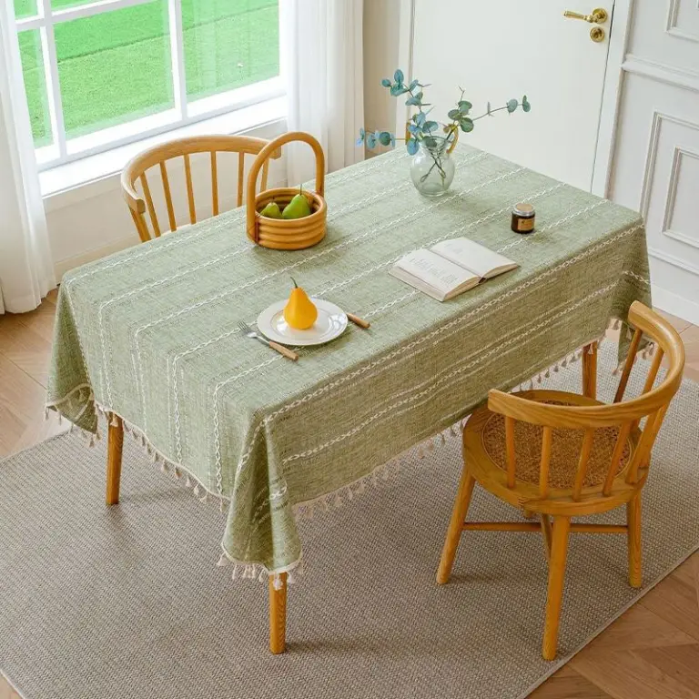 Grüne Tischdecke mit weißen Streifen und Quasten auf rechteckigem Esstisch mit Stühlen