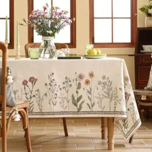 Beige Tischdecke mit Wildblumen-Motiv und Bordüre auf Esstisch mit Holzstühlen